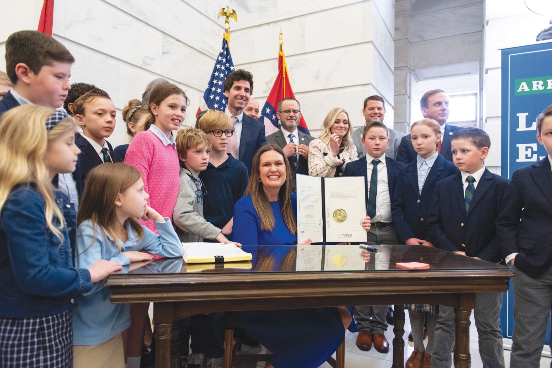 Arkansas Governor Sarah Huckabee Sanders surrounded by a group of students from Calvary Academy at the Arkansas State Capital while she signs the bill into law. photos courtesy of Sarah Huckabee Sanders