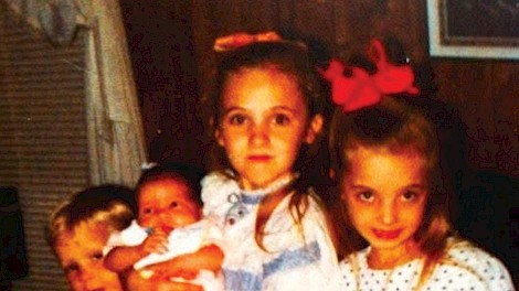 Vonnie with her siblings, from left to right—Bradley, baby Brittany held by Brandie, and Vonnie wearing a red bow and belt
