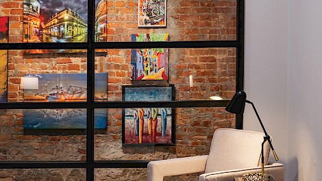 From the master bedroom, the view opens to a gallery-style hallway framed by preserved brick and accented with custom art.